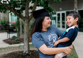 PelotonU student, Wendy, wearing a cap and holding her son Trae